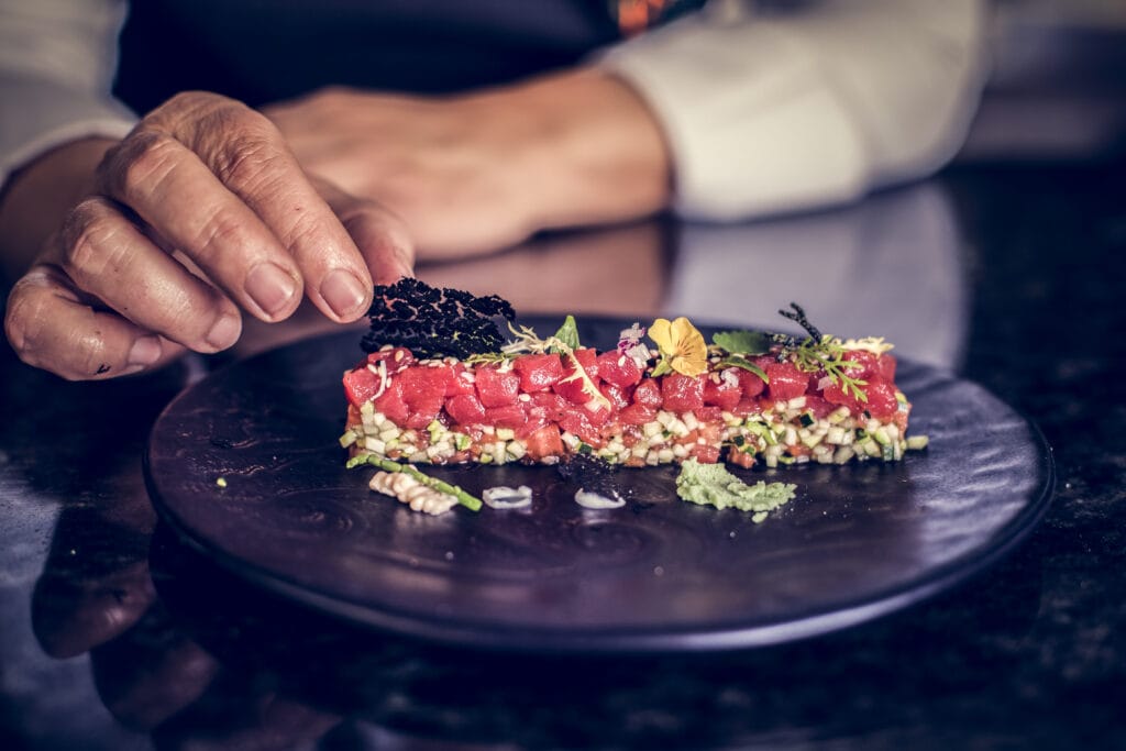 Manipulando un plato de tartar de tomate con hierbas y flores