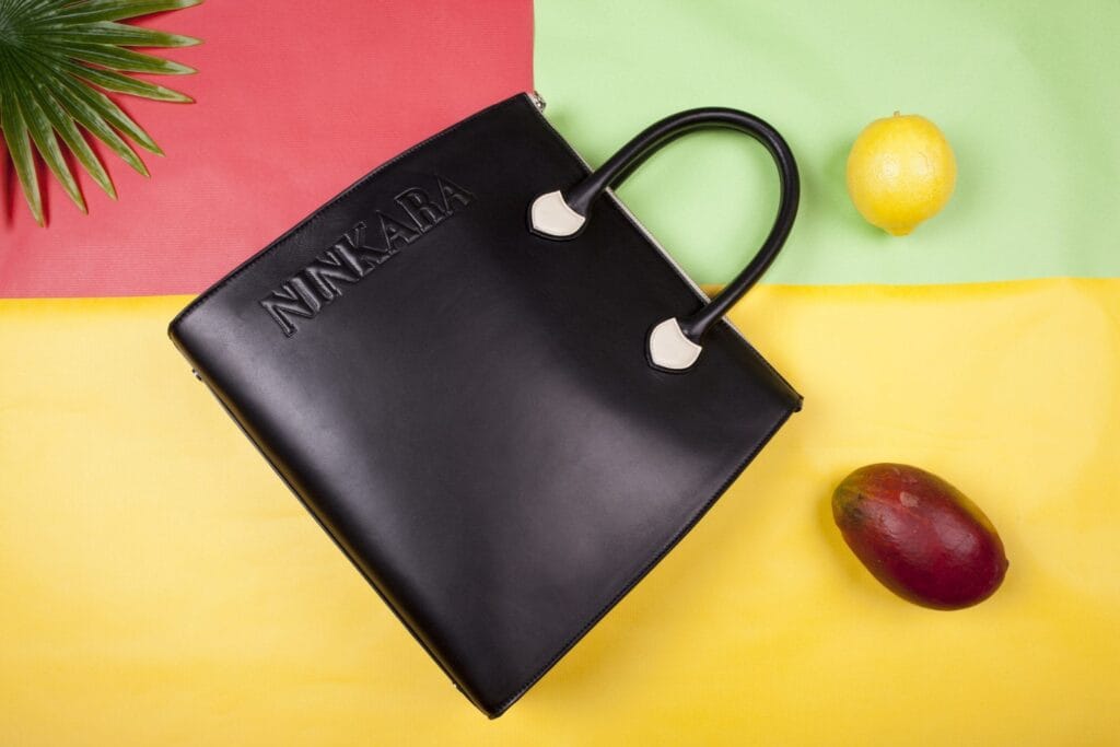 Bolsa de mano negra con el nombre NINKARA en relieve.
