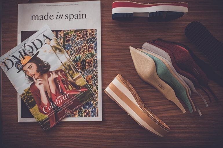 Zapatos y revistas de moda sobre una mesa de madera.