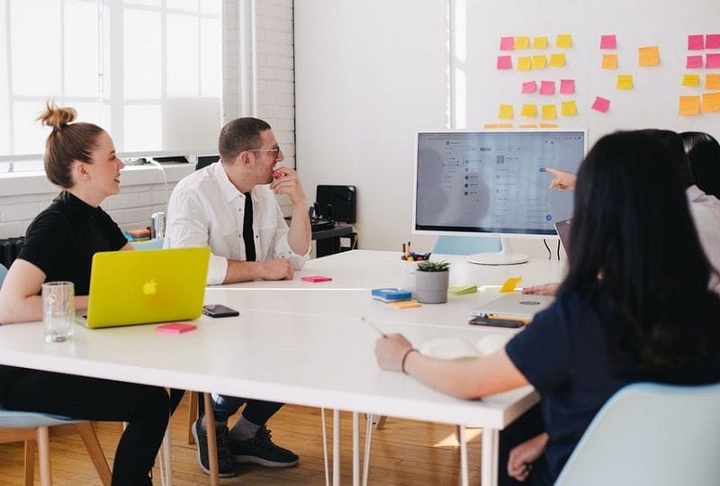 Tres personas en una reunión de trabajo en una oficina.