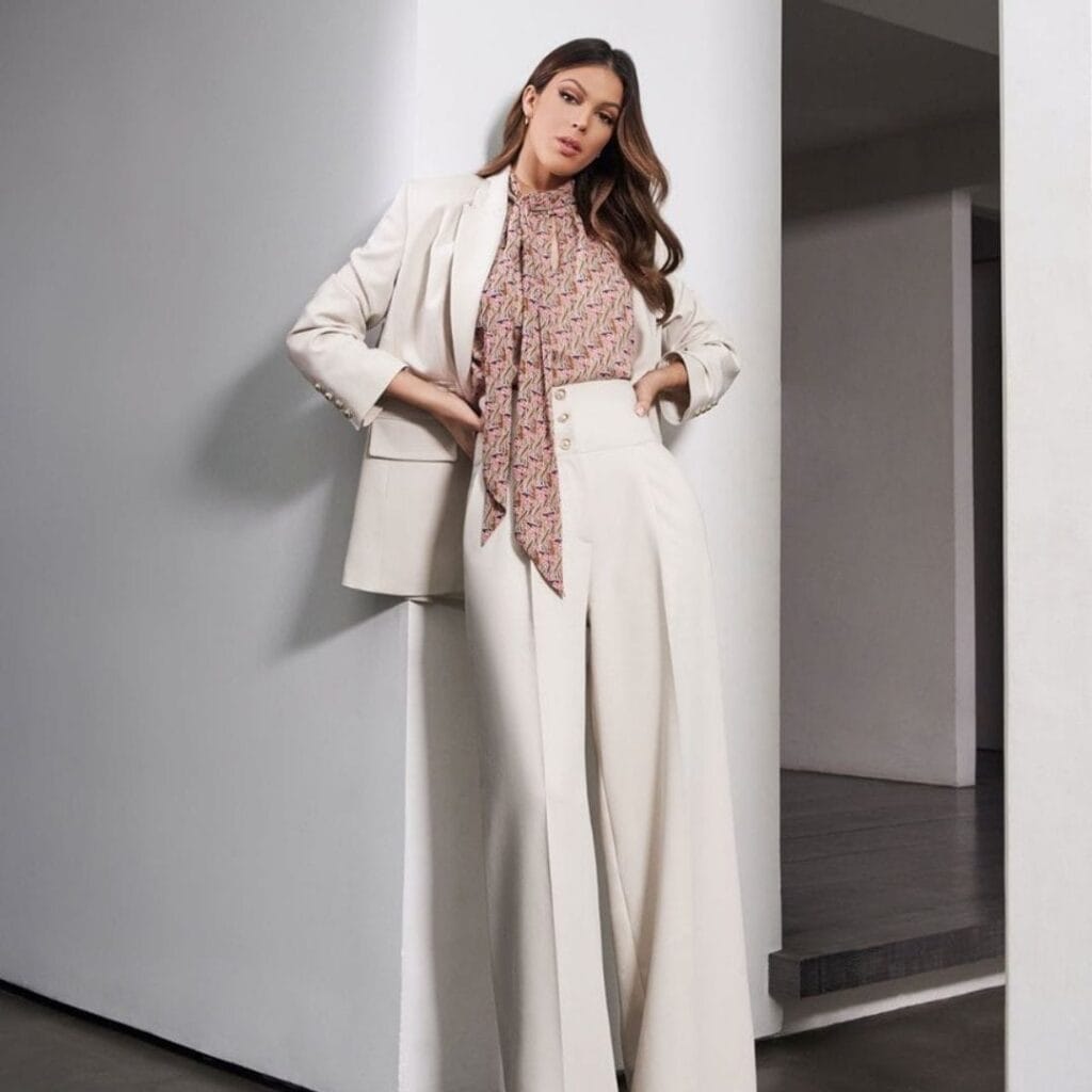 Mujer elegante con traje blanco y blusa estampada.